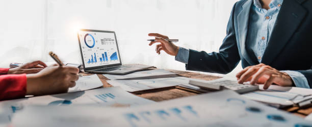 istock Business People Meeting using laptop computer,calculator,notebook,stock market chart paper for analysis Plans to improve quality next month. Conference Discussion Corporate Concept 1483799167