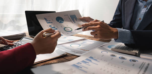 istock Business People Meeting using laptop computer,calculator,notebook,stock market chart paper for analysis Plans to improve quality next month. Conference Discussion Corporate Concept 1483799184