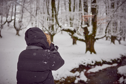 Photographer in a snowy forest of pines in The Basque Country, North of Spain