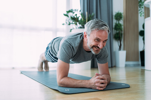 Smiling mature man working out at home.