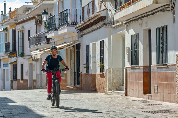 woman cycling in the white village of Frigiliana, Andalusia, Spain stock photo