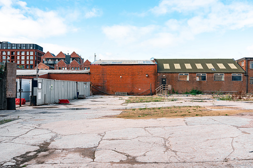 Abandoned multi-story brick factory building with broken glass windows.