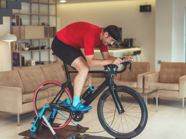 istock A man riding a triathlon bike on a machine simulation in a modern living room. Training during pandemic conditions. 1483809312