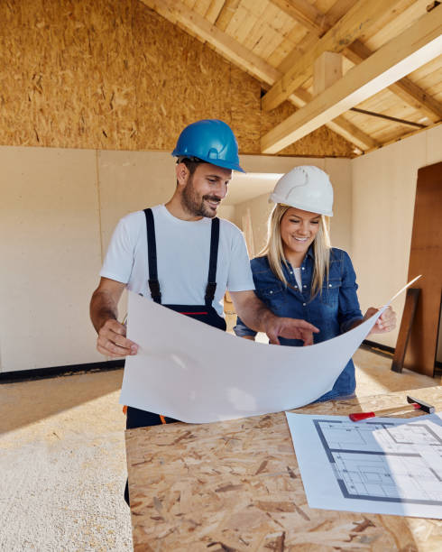 istock Happy female architect and manual worker analyzing blueprints at construction site. 1483809868