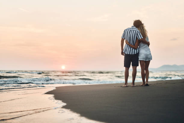 istock Back view of affectionate couple embracing on the beach at sunset. 1483811256