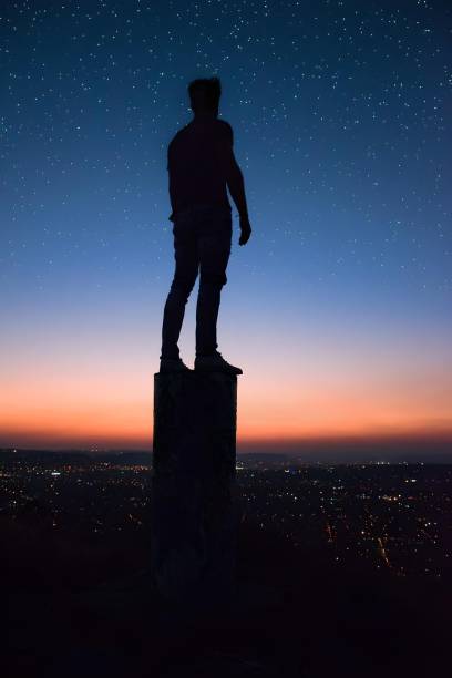 istock Silhouette of a man standing on a post, looking up at the night sky 1483811277