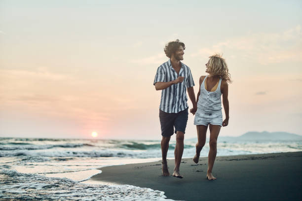 istock Young cheerful couple running on the beach at sunset. 1483811567