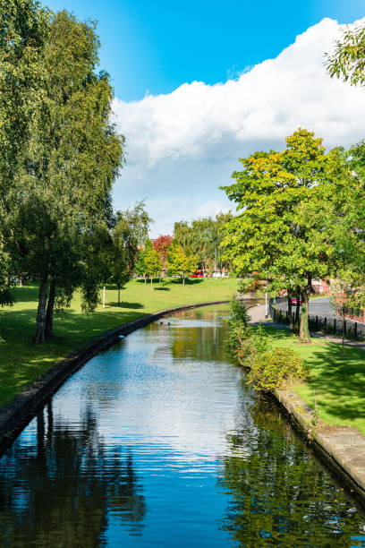 A single crewed boat sculling along the ship canal in Manchester, England