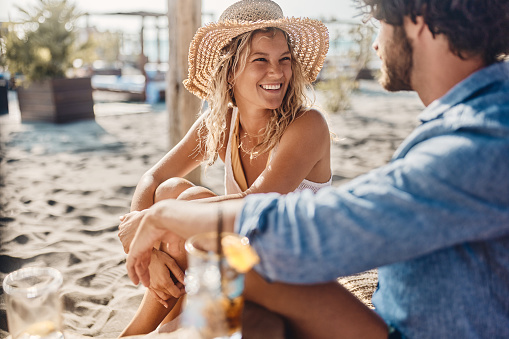Young happy woman communicating with her boyfriend during summer day on the beach.
