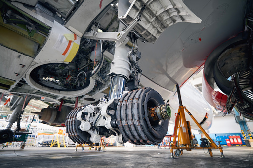 Commercial airplane under heavy maintenance. Close-up of landing gear of plane during repair.