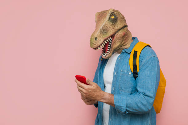 istock Man with backpack and lizard mask on pink background, he is using the smart phone. 1483814995