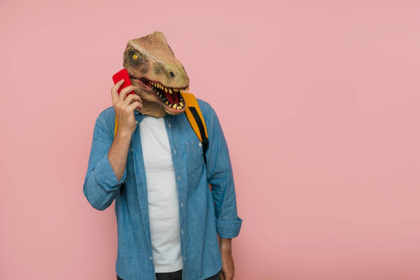 istock Man with backpack and lizard mask over pink background using phone. 1483815019