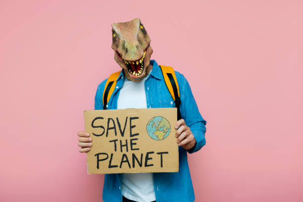 istock Man with backpack and lizard mask on pink background holds sign to save the planet. 1483815026