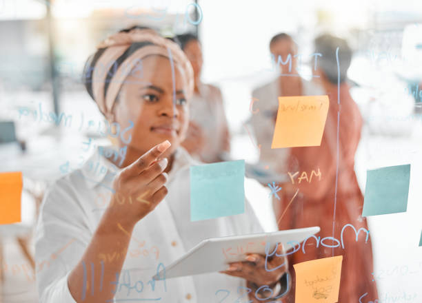 istock Planning, thinking or black woman for brainstorming on tablet with sticky notes, planning or creative idea on glass wall. Focus, teamwork or business meeting with writing, reading or work schedule 1483817274