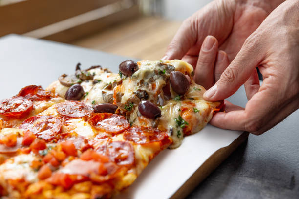 istock Breaking off a piece of pizza in rectangular shape from a tray on the table 1483818270