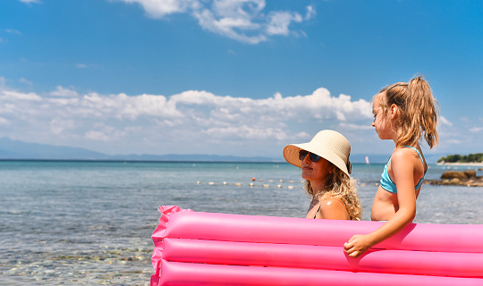 Mother and daughter sit on a floating bed and sunbathe