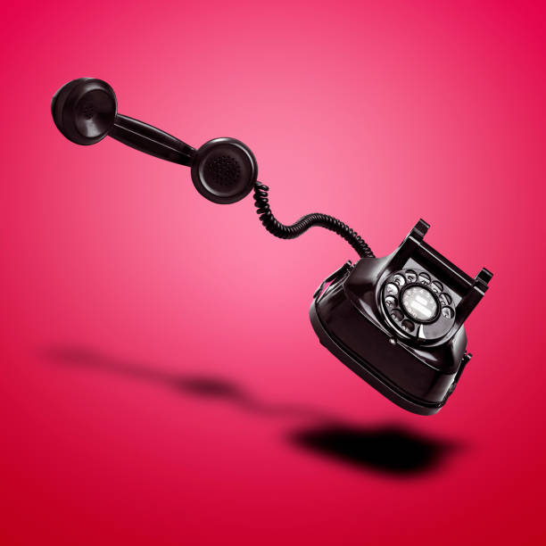 istock Floating  Old black telephone with shadow against red gradient background 1483820208
