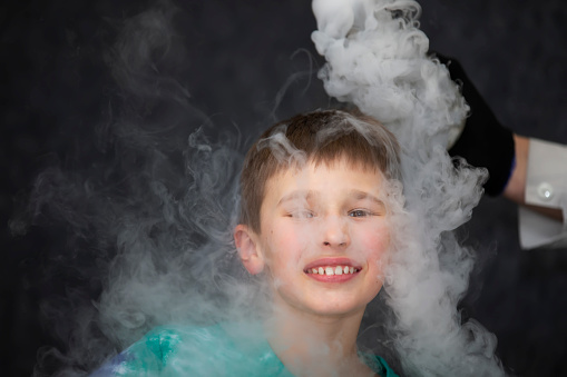 The child is a participant in scientific experiments. A boy in liquid nitrogen smoke.