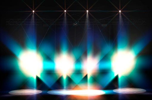 Bright beams of light from stage lights on a dark background.