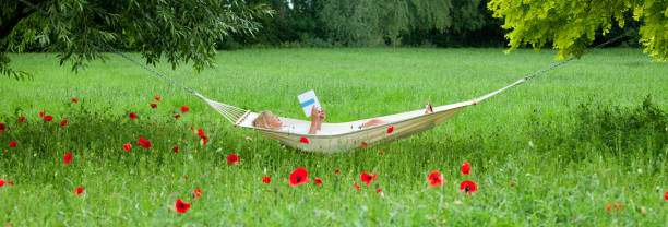 Lazy time. Man in hat in a hammock with book on a summer day