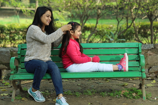 Mother and daughter enjoying in park surrounded with greenery and serenity. They are having joyful and cheerful time together in green environment. Loads of smile and happy moments.