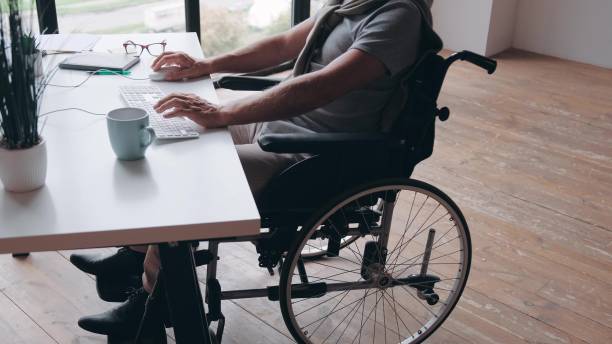 istock Businessman Sitting In Wheelchair Using Computer At Workplace 1483830590