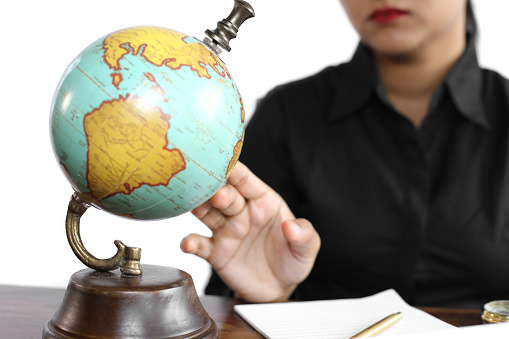 Young female in casual wear turning globe at her workplace.