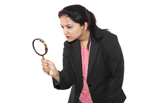 Young woman in casual wear using magnifying glass.