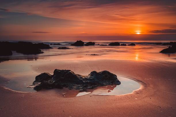 istock Stunning sunset over a beach with rocks on the sandy shoreline. 1483832181