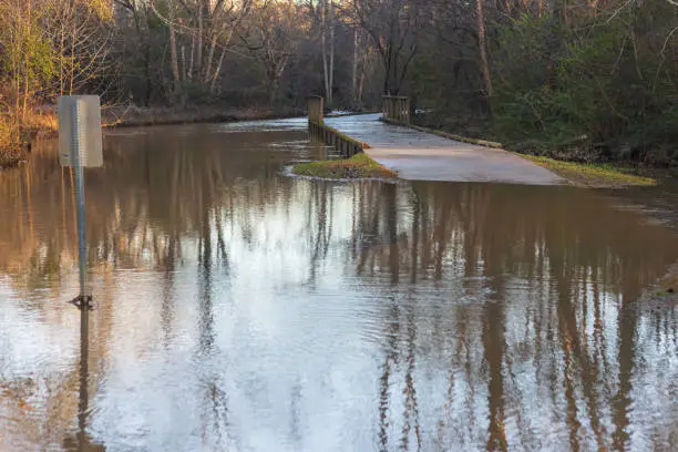 A walkway and sign are partially submerged from a nearby creek flooding from torrential rains.