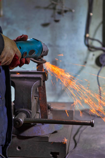 istock One Man Fitter in Protective Gloves and Uniform With Gringer Tool For Metal Work With Bunch of Sparks in Workshop. 1483838642
