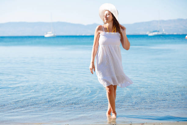 Happy woman in white dress enjoys tropical beach vacation