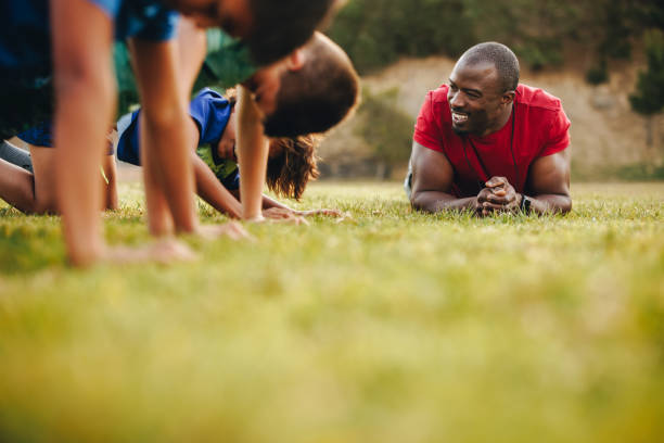 Happy school coach training a rugby team in a field