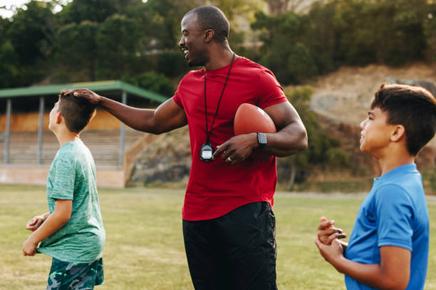 istock Elementary school coach playing American football with his students 1483845884