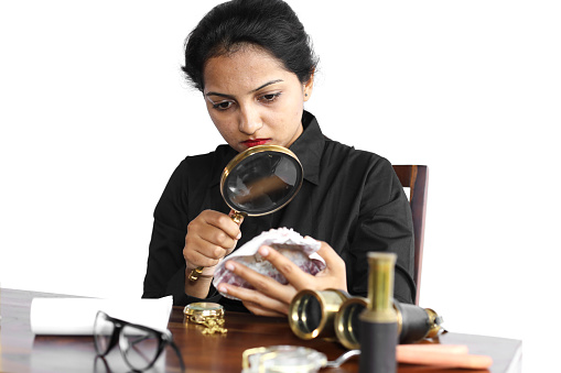 Young female archaeologist in casual wear inspecting an animal shell using a magnifying glass.