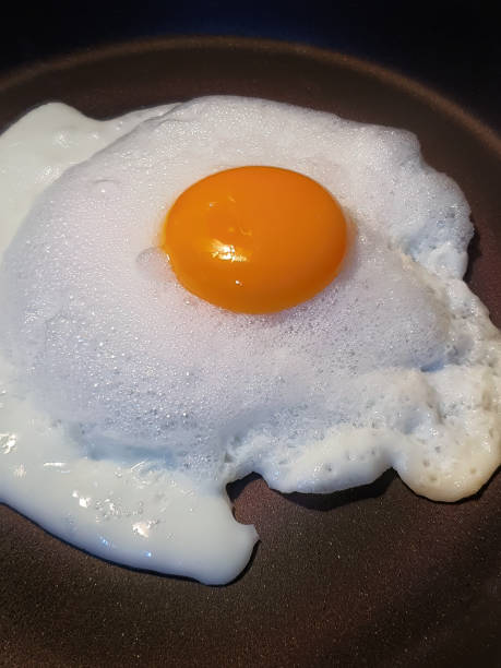 istock Close up fried egg in dark color frying pan, sunny side up, fluffy bubble white egg style, egg yolk, healthy food, cooking, diy, daily breakfast 1483853400