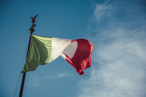 Italy flag waving in the wind on the blue sky background.
