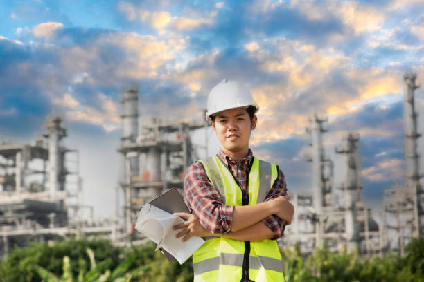 istock Engineer wearing white helmet holding paper drawing with oil refinery background.Engineer Concept,professional,safety,industry 1483863486