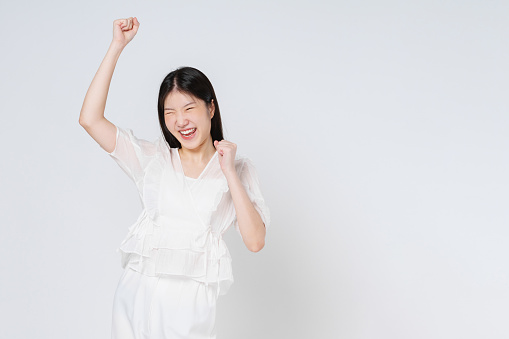 Young asian woman with raised hands celebrating success isolated on white background.