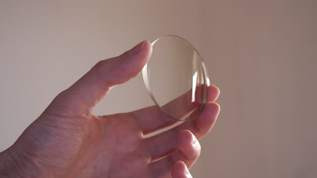 Hand holding glass lens for eyewear