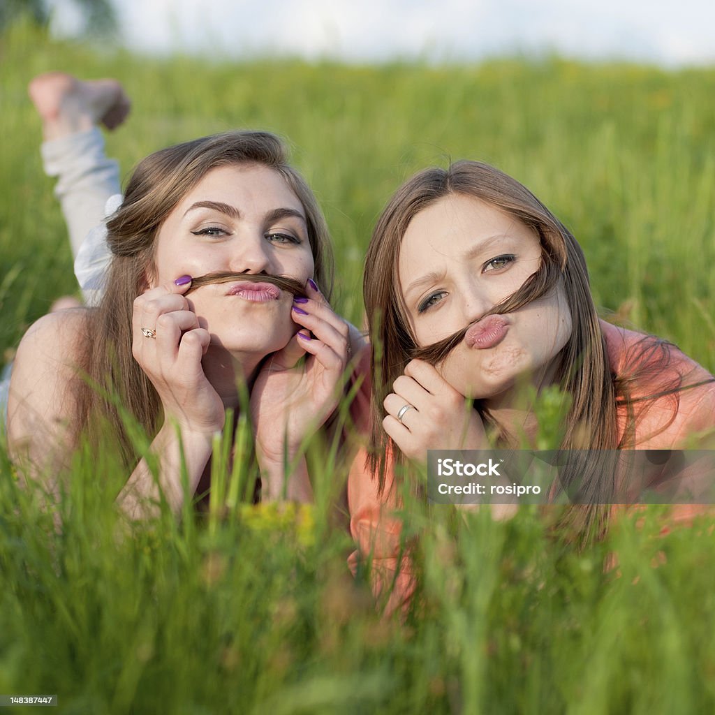 Two happy teenage friends Two happy teenage girl friends having fun with hair in green grass Adult Stock Photo