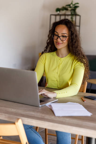 istock Smart young woman sitting at dining table, using laptop when managing home finances 1483874739