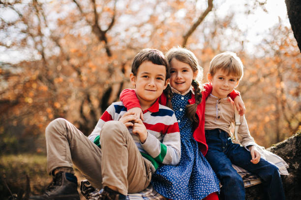 istock Children sitting on a tree in autumn forest 1483875806