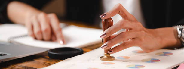 istock Person's hand stamping with approved stamp on certificate document public paper agreements at desk of notary or business people work, businesswoman making a signs permit on paper work business success 1483877931
