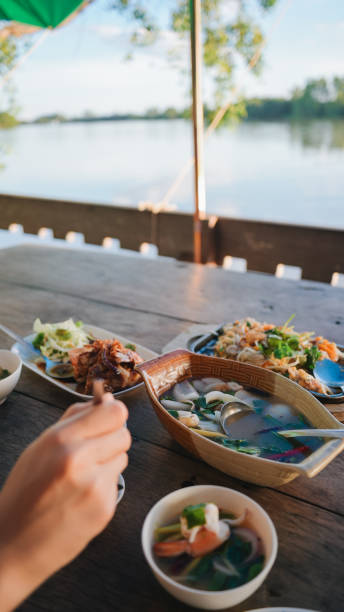 자연 강 전망과 함께 야외에서 태국 음식과 해산물을 즐기는 젊은 태국 사람들 - thai cuisine thailand asian cuisine chinese cuisine 뉴스 사진 이미지