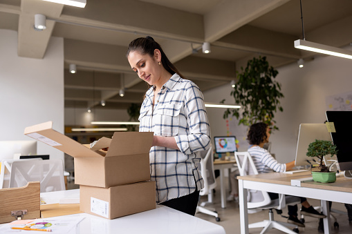 Waist up portrait of smiling young businesswoman holding box of personal belongings  leaving office after quitting job, copy space