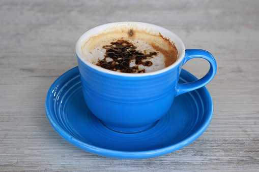 A blue cappuccino mug on a grey wooden table.