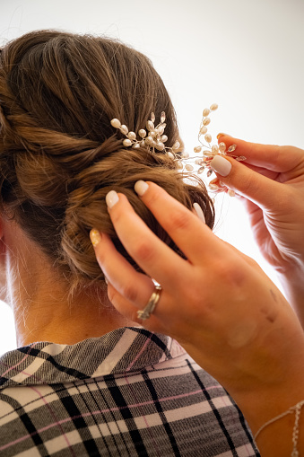 A close up of a hair dressers hands putting the final touches on a brides hair.