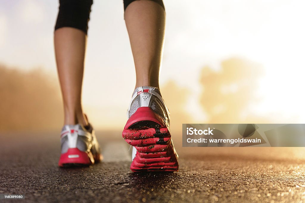 Runner feet sunrise Runner feet running on road closeup on shoe. woman fitness sunrise jog workout wellness concept.  Dress Shoe Stock Photo