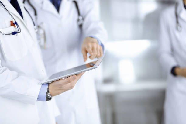 istock Group of unknown doctors use a computer tablet to check up some medical names records, while standing in a hospital office. Physicians ready to examine and help patients. Medical help, insurance in health care, best desease treatment and medicine concept 1483892887